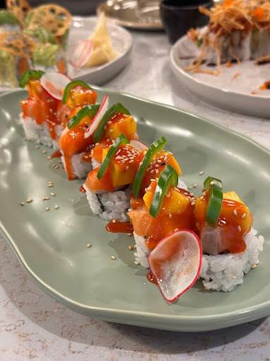 Mango Tango Roll in the Special Roll section made with Aavocado, tuna topped with salmon, mango, jalapeno, and spicy sauce